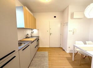 Une cuisine compacte avec des meubles en bois, un plan de travail, un évier et un coin repas comprenant une table et des chaises.