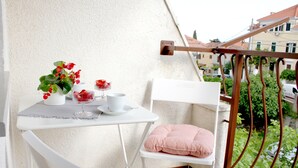 A small balcony with a white table, a chair, a potted plant, and a cushion. - Marjan Hill Apartment - close to center & own garage (Split)
