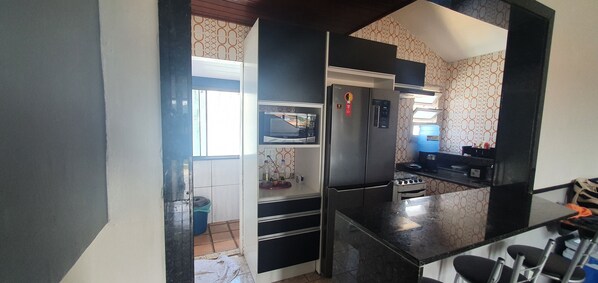 Cocina pequeña con refrigerador, microondas y estufa.
