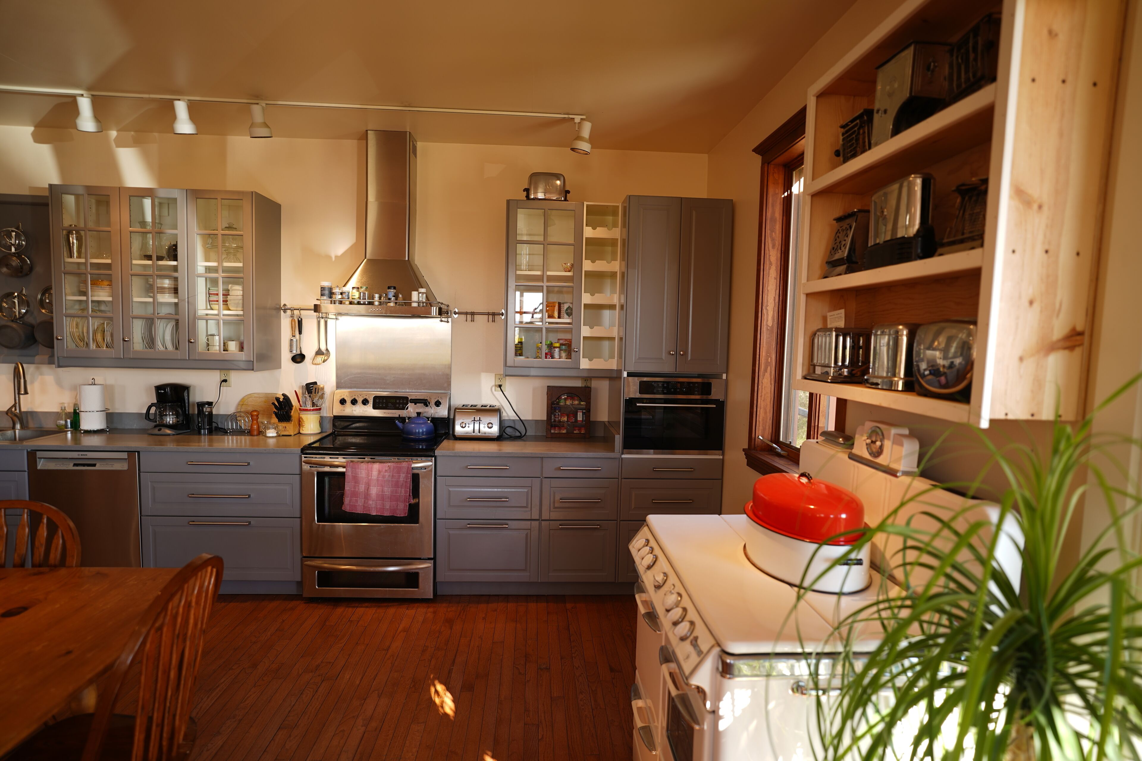 A kitchen with grey cabinets, a stove, and a sink.