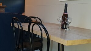 A dining area with a wooden table, four black chairs, a bottle of champagne, and two wine glasses. - Lockleigh Park - Escape to the Country (Lebrina)