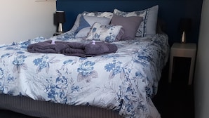 A neatly made bed with a floral duvet cover, a dark throw blanket, and several pillows. - Lockleigh Park - Escape to the Country (Lebrina)
