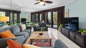 Ein modernes Wohnzimmer mit Sofa, Couchtisch, Fernseher und Deckenventilator.