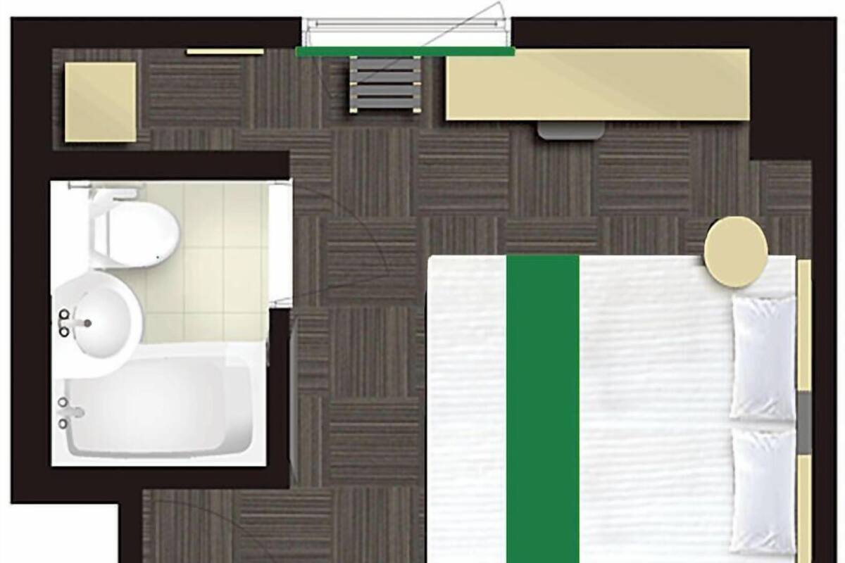 A hotel room with a bed, a bathroom with a toilet and sink, and a small sitting area.