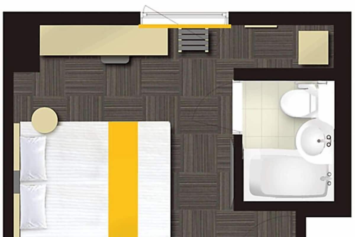 A hotel room with a bed, a bathroom, and a small sitting area.