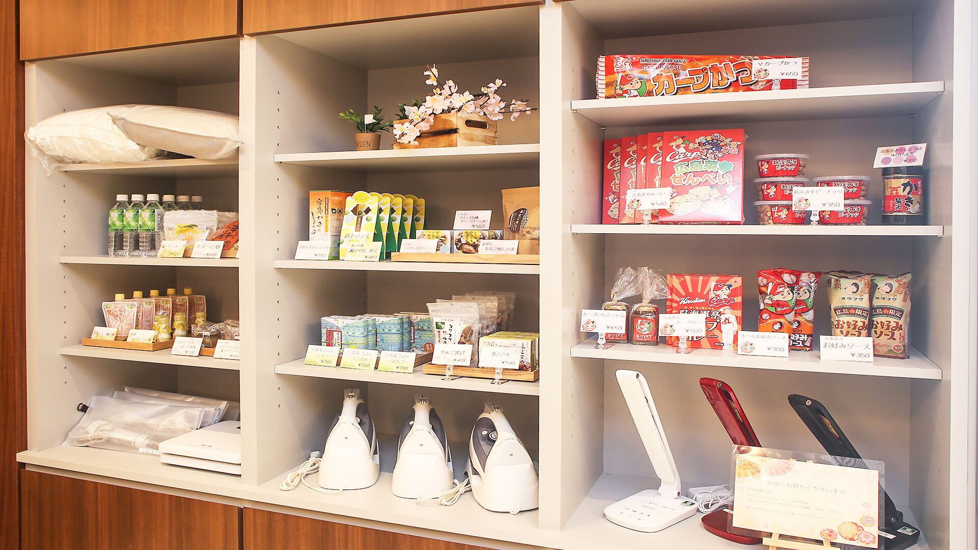Una tienda con estantes llenos de diversos productos, entre ellos alimentos, artículos del hogar y productos de cuidado personal.