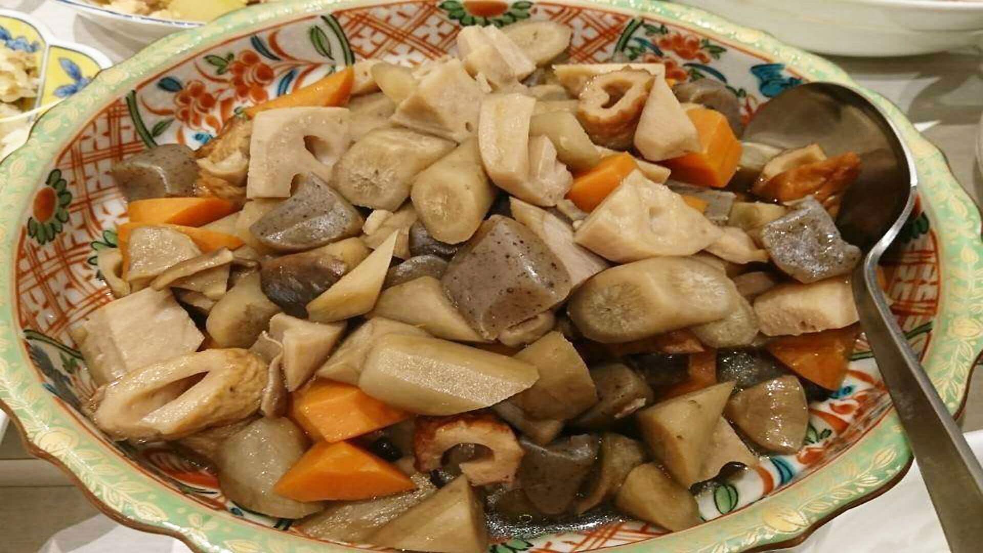 A bowl of cooked vegetables and meat, possibly a stew, on a patterned plate.