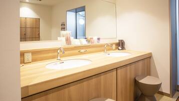 A modern bathroom with two sinks, a large mirror, and wooden cabinetry.