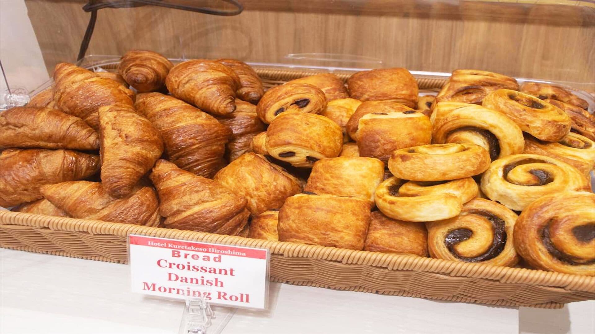 Une présentation de petits pains, de croissants et de viennoiseries dans un panier en osier.