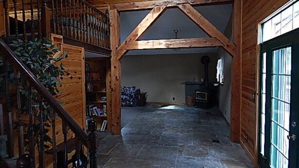 A wooden interior with a stone floor, a staircase, and a door with glass panels.