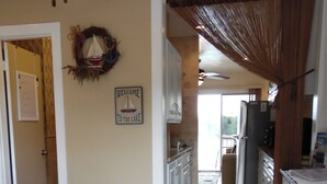 Un pasillo estrecho que lleva a una cocina y un dormitorio con una cama y un banco de madera.
