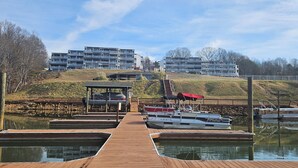 Un puerto deportivo con barcos amarrados, un muelle de madera y edificios de apartamentos al fondo.