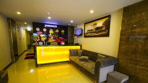 A hotel reception area with a bright yellow counter, a sofa, and a wall-mounted TV. - Saigonciti Hotel (Ho Chi Minh City)
