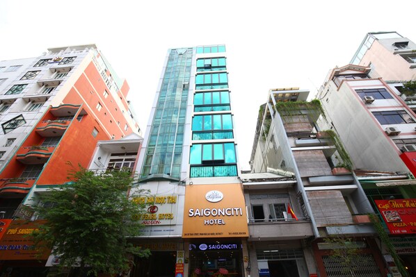 Un hotel con fachada de vidrio moderna, un llamativo letrero naranja y varios balcones.