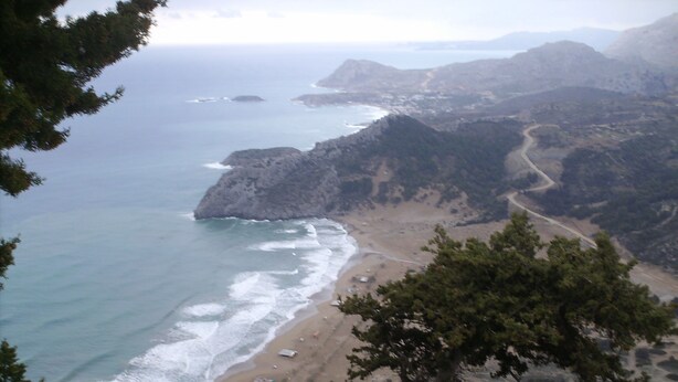 Un paysage côtier avec une plage, des falaises rocheuses et une route sinueuse.