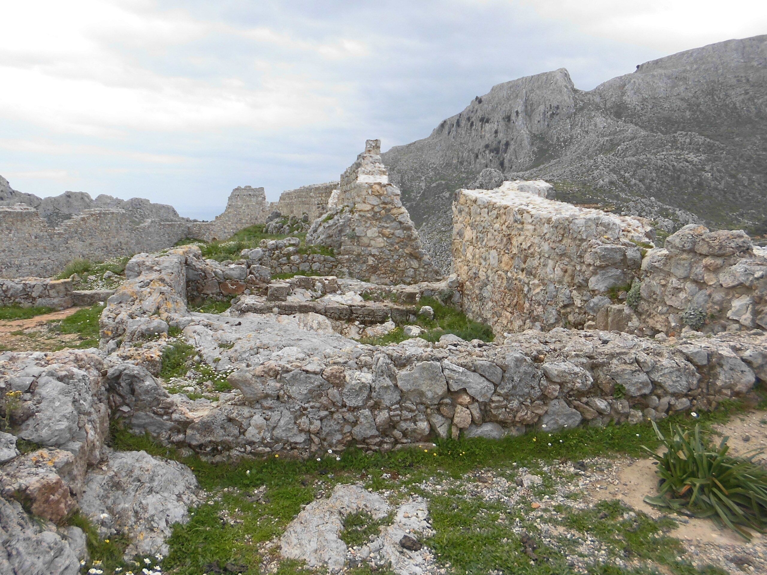 Ancient stone ruins with rugged terrain and sparse vegetation.