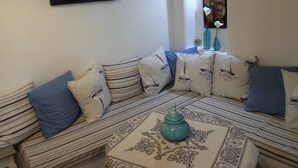 Un salon chaleureux avec un canapé agrémenté de coussins à rayures, un chemin de table à motifs et un vase décoratif.