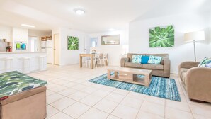 Ein modernes Wohnzimmer mit Sofa, Couchtisch und einem Essbereich mit Stühlen und Tisch.