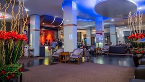 A hotel lobby with a reception desk, seating area, and decorative elements like red flowers and abstract wall art. - Atrium Boutique Hotel (Bangkok)