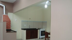 A kitchen with a stove, oven, and a small dining area with a chair. - House with pool, barbecue, air conditioning. (Caraguatatuba)