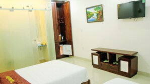 A hotel room with a bed, a small table, a TV, and a wardrobe. - Tram Huong (Da Nang)