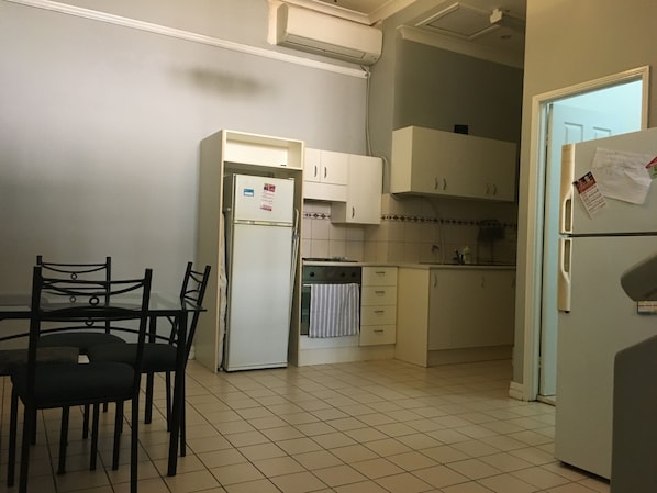 Enjoy meals at the dining table in this kitchen, equipped with a refrigerator and air conditioning for your comfort.
