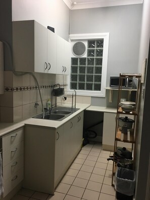 Compact kitchen with sink, microwave, and cabinets.