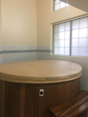 Relax in a spacious room with a large round bathtub and frosted glass window for a view.