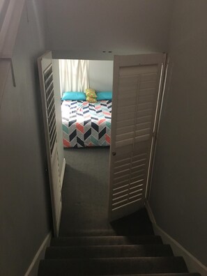 Stairs lead to a cozy bedroom with a bed and window.