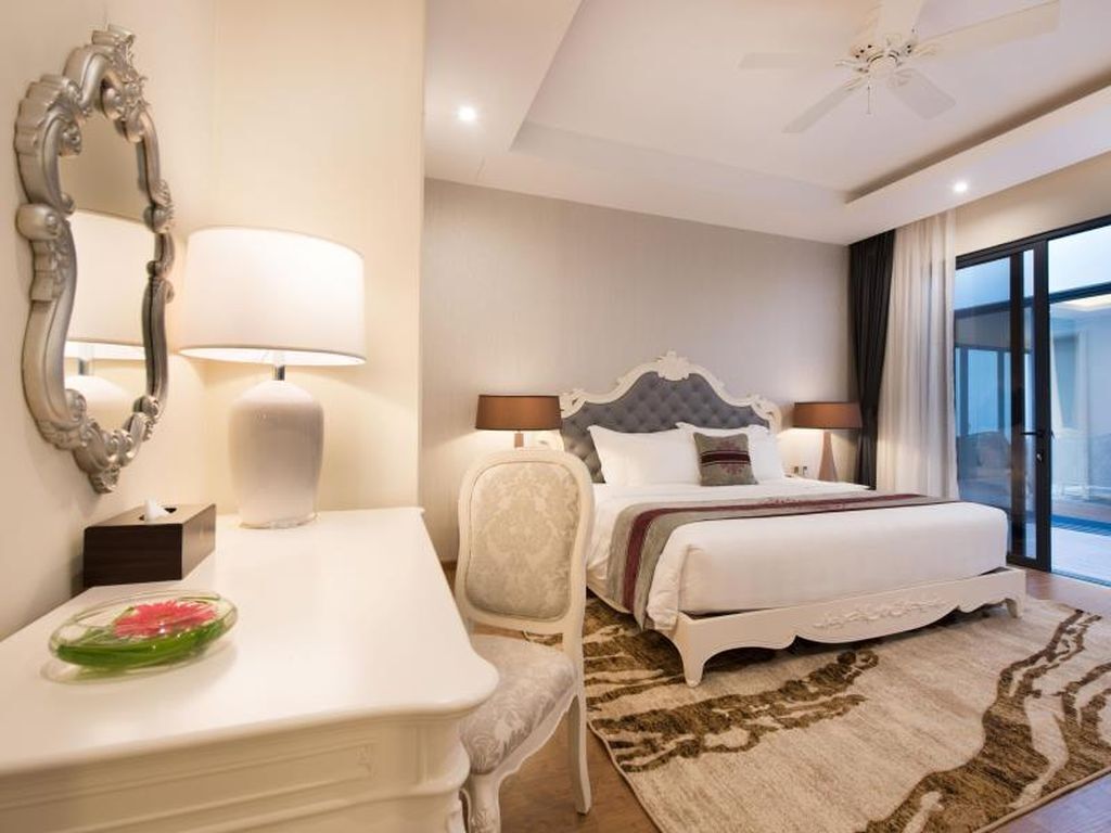 A hotel room with a bed, bedside tables, a mirror, and a view of the outside.