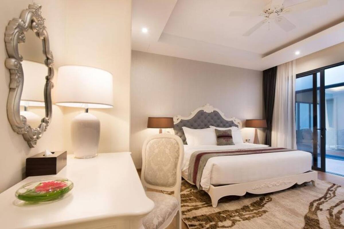 A hotel room with a bed, bedside tables, a mirror, and a view of the outside.