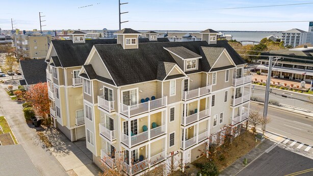 Un immeuble résidentiel à plusieurs étages, doté de balcons, offrant une vue sur le front de mer et donnant sur une rue.