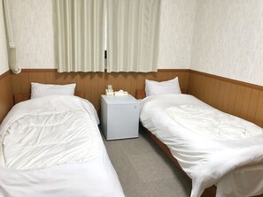 A hotel room with two single beds, a small bedside table with a phone and tissues, and a wall-mounted heater. - Pension Lanpou (Fujikawaguchiko)