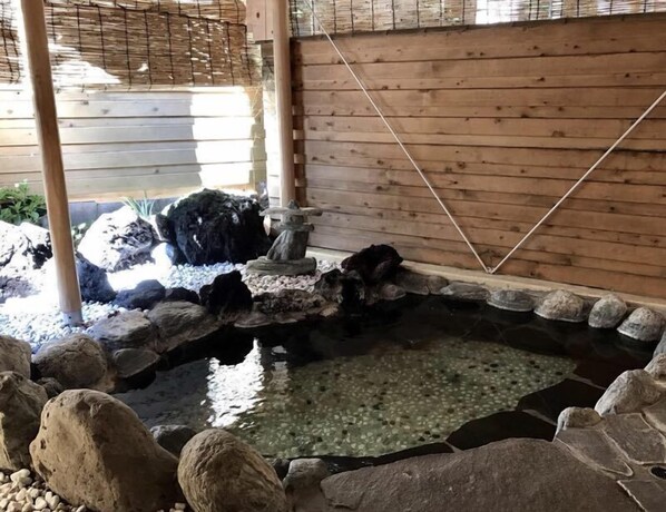 Un pequeño estanque con rocas y una valla de madera al fondo.