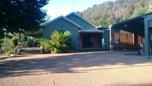 A two-story building with a covered porch and a garage. - Riverbend Homestead Horse and Farmstay (Freeburgh)
