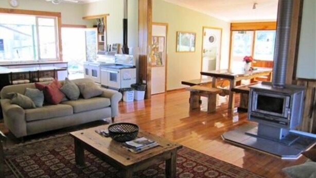 A living room with a sofa, coffee table, and a fireplace. - Riverbend Homestead Horse and Farmstay (Freeburgh)
