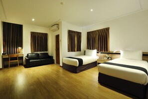 A hotel room with two beds, a desk, a chair, and a wardrobe.