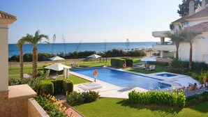 A swimming pool with a view of the sea, surrounded by palm trees and a well-maintained lawn. - 102 Luxury Serv Apart-Estepona 3 Bed, 28c Heated 20m Pool, Jacuzzi - an Oasis (Estepona)