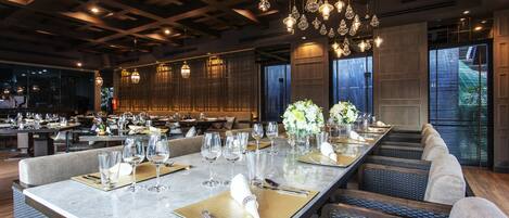 A modern dining area with long tables, elegant lighting, and comfortable seating.