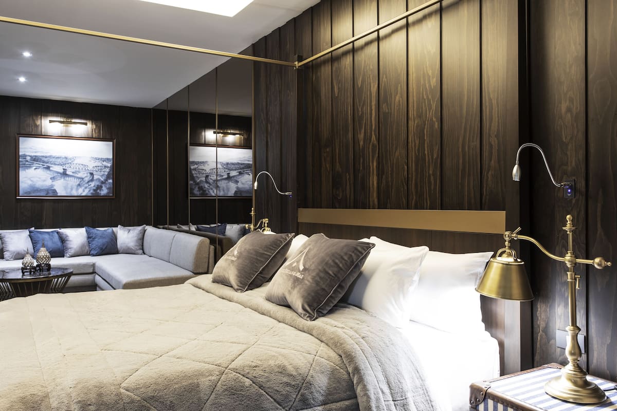 Une chambre d’hôtel moderne équipée d’un grand lit, d’un canapé-lit, d’un bureau et d’une table de chevet.