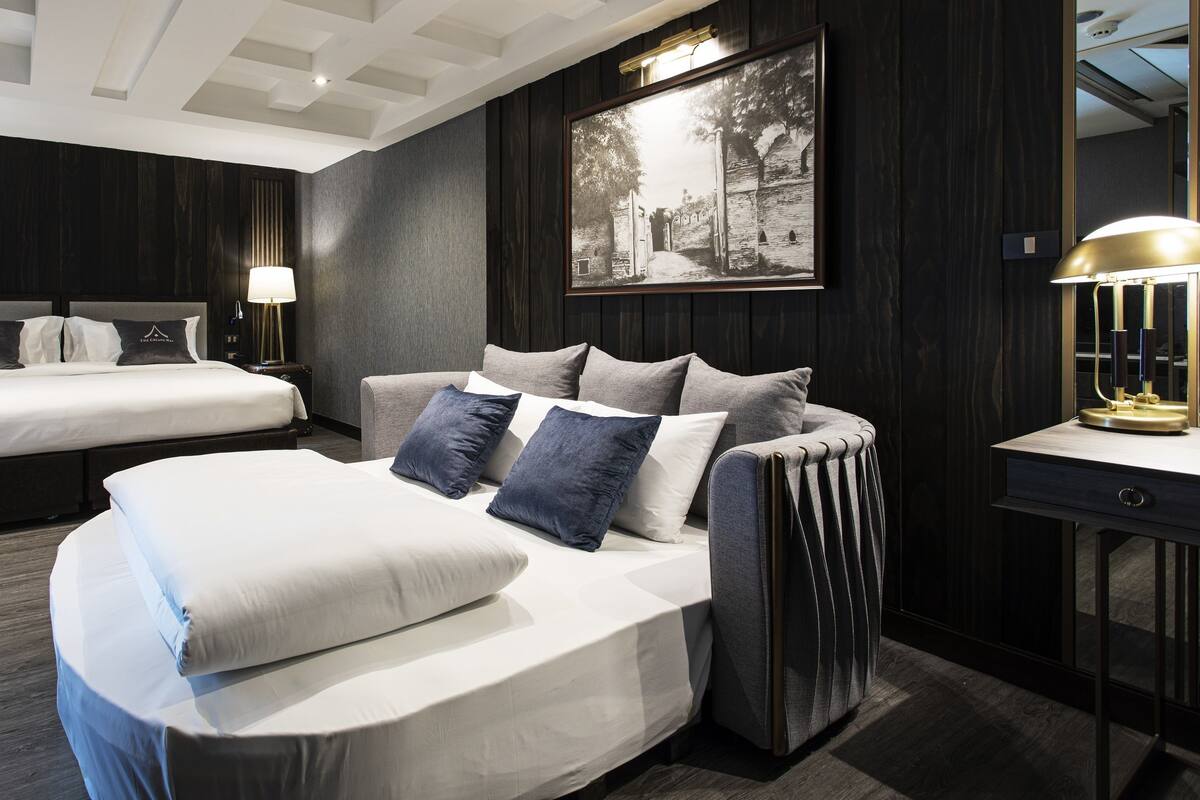 Une chambre d’hôtel moderne avec un grand lit, un canapé-lit et un bureau avec une lampe.