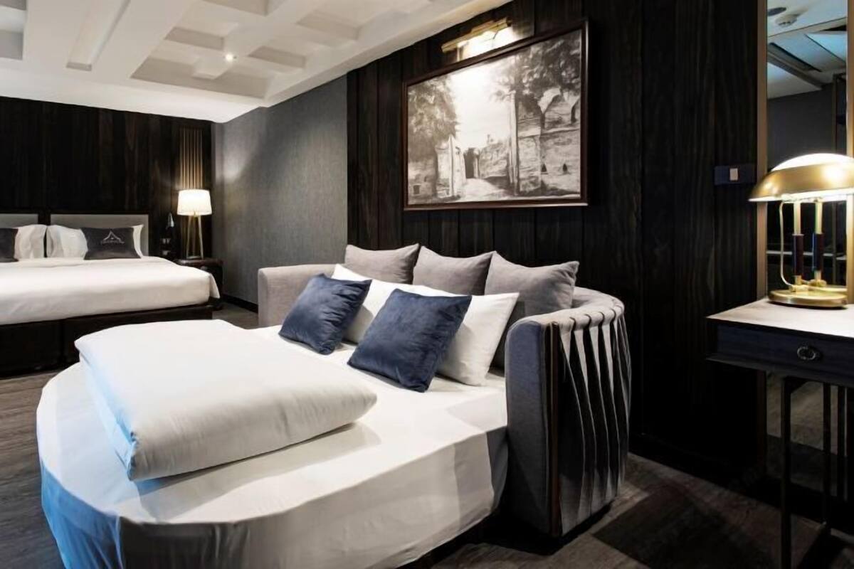 Une chambre à coucher moderne avec un lit, un canapé, un bureau et une lampe.