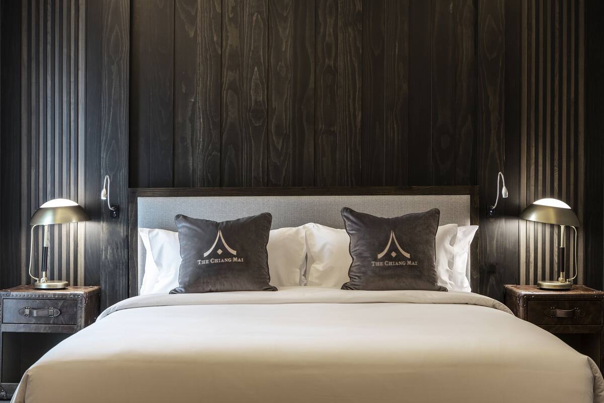 Une chambre d’hôtel avec un grand lit, deux tables de chevet et deux lampes.