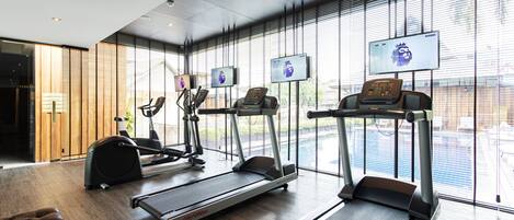A modern gym with treadmills, elliptical machines, and a rowing machine.