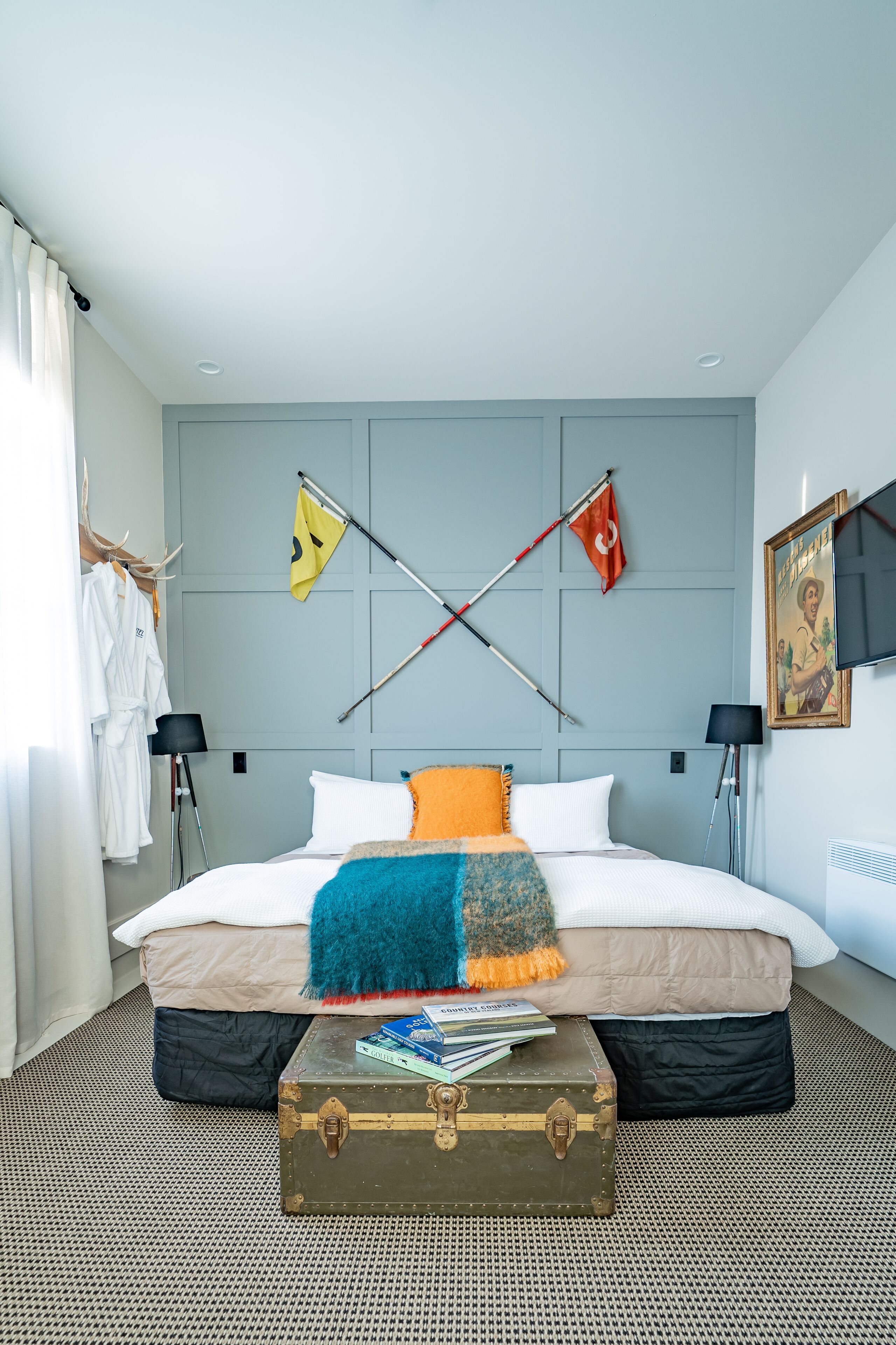 A hotel room with a large bed, a suitcase, and two flags on the wall.