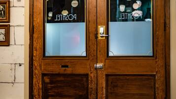 A wooden double door with frosted glass panels and an EXIT sign above.