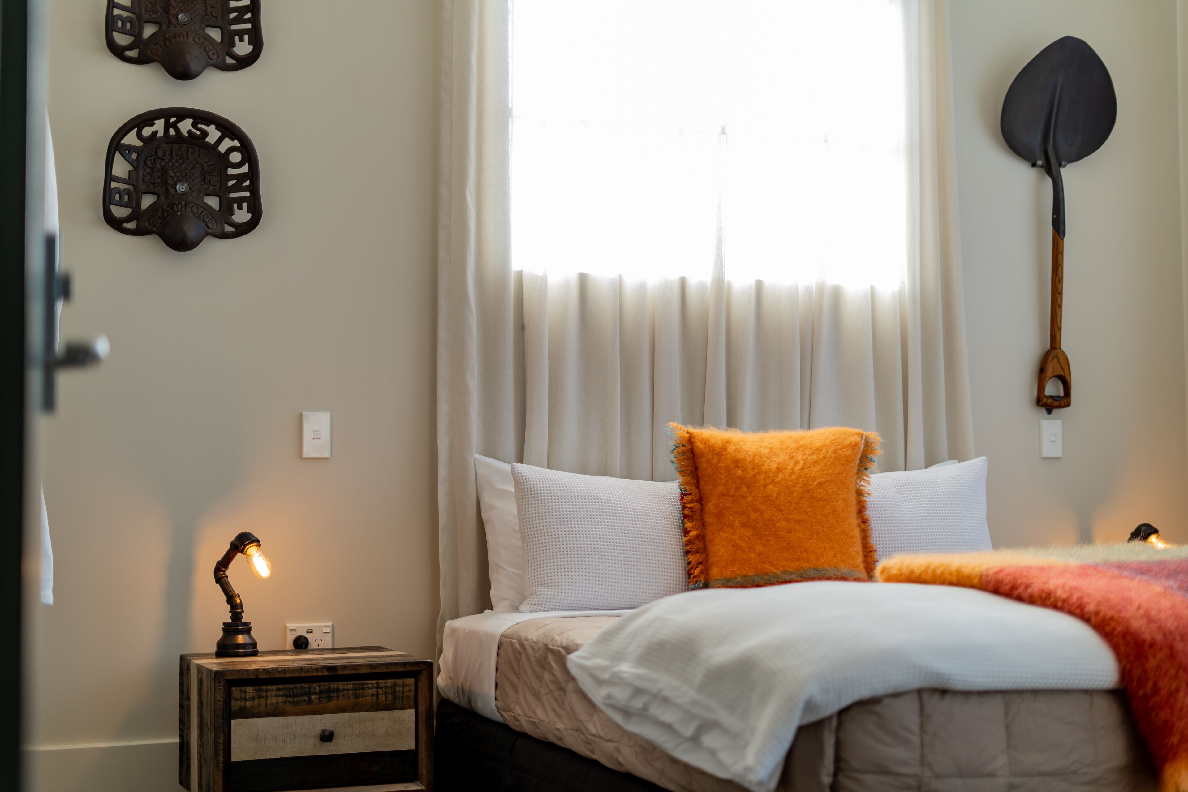 A bedroom with a bed, a nightstand, a lamp, and a window with curtains.