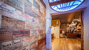 Eine Wand mit Whisky-Etiketten in einem Raum mit Holzboden und einer Treppe, die in einen weiteren Bereich führt.