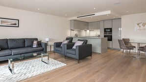 A modern living room with a sofa, two armchairs, a glass coffee table, and a dining area with a table and chairs. - A luxury, contemporary 2Bed & 2Bath Apartment Next to London Museum (London)