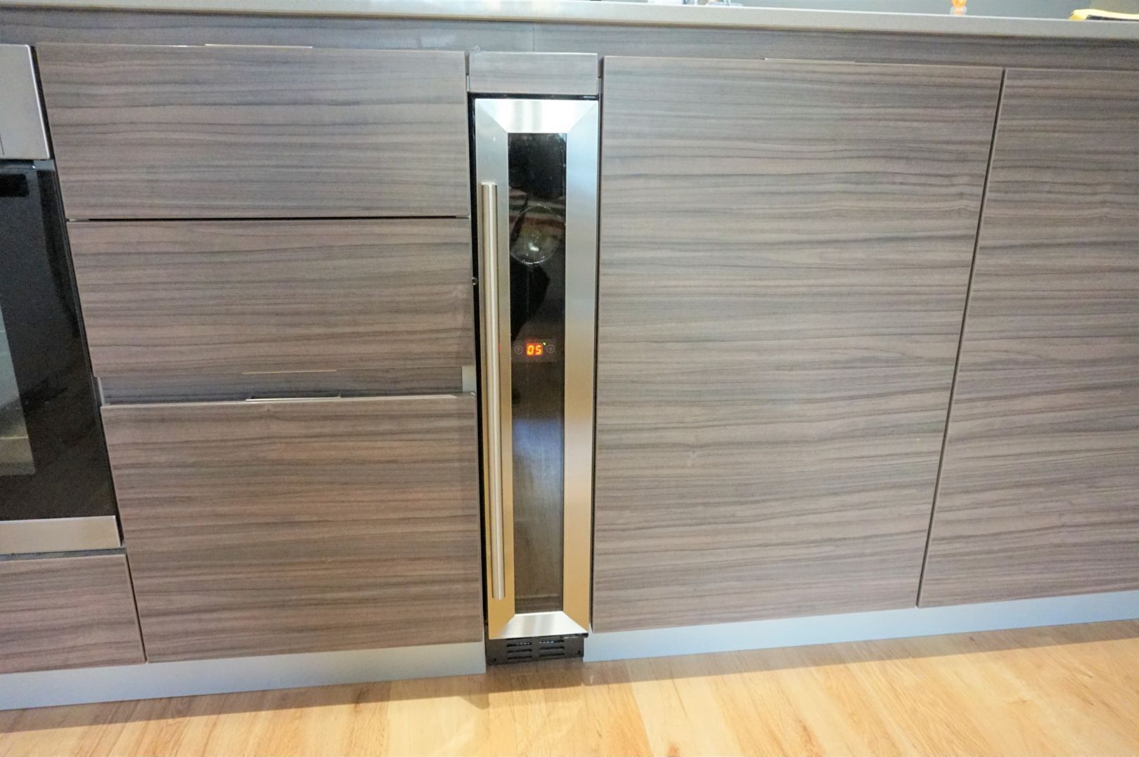 A kitchen with a built-in stainless steel refrigerator, wooden cabinets, and a wooden countertop.